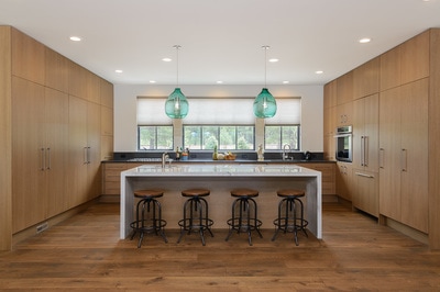 Interior kitchen image of barstools at kitchen island with beautiful teal pendants in glass at Custom home in Bend Oregon built on private acreage in modern farmhouse style by Structure Development NW a home builder in Central Oregon.